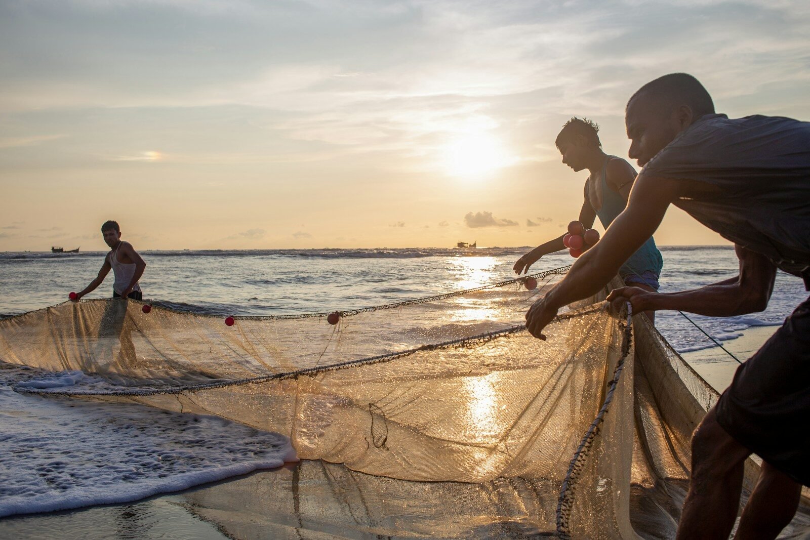 Home A group of people standing on a beach next to a net